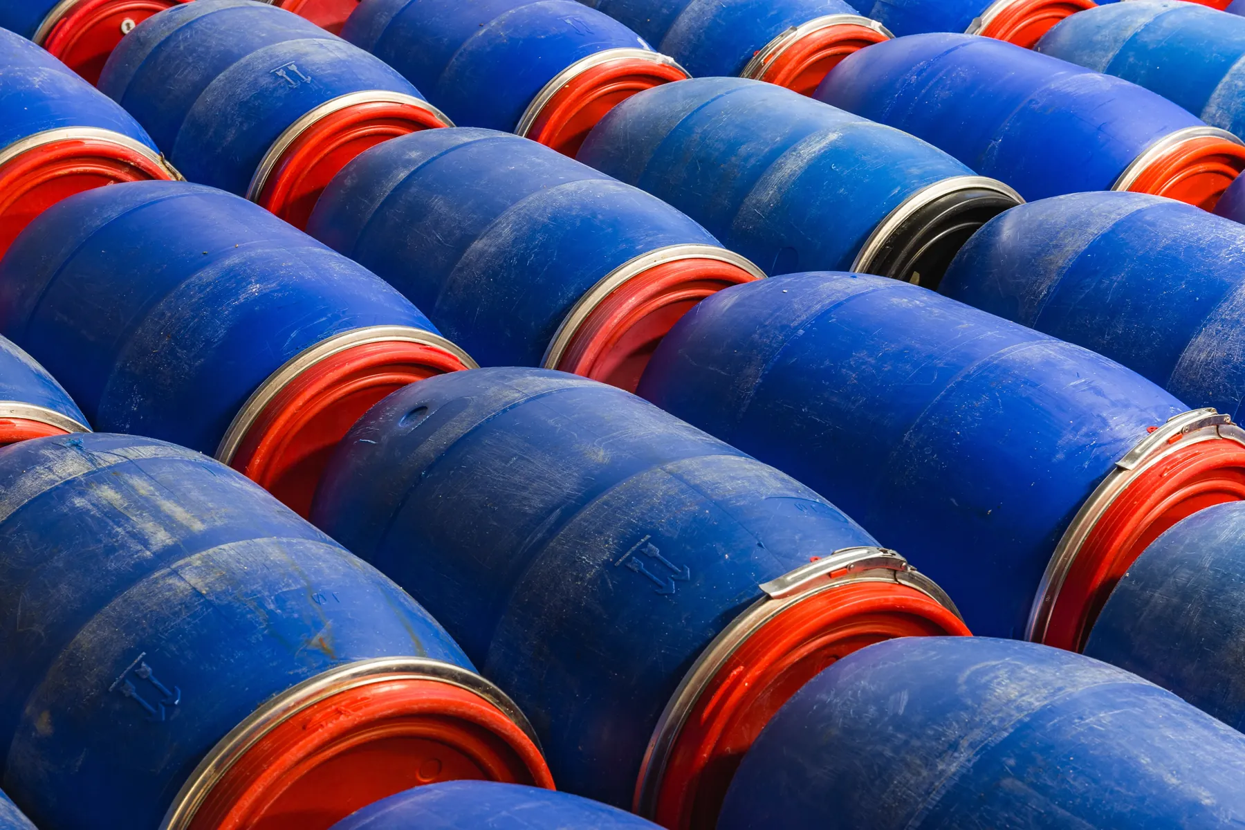 Tambores de produto químico armazenados em área industrial.